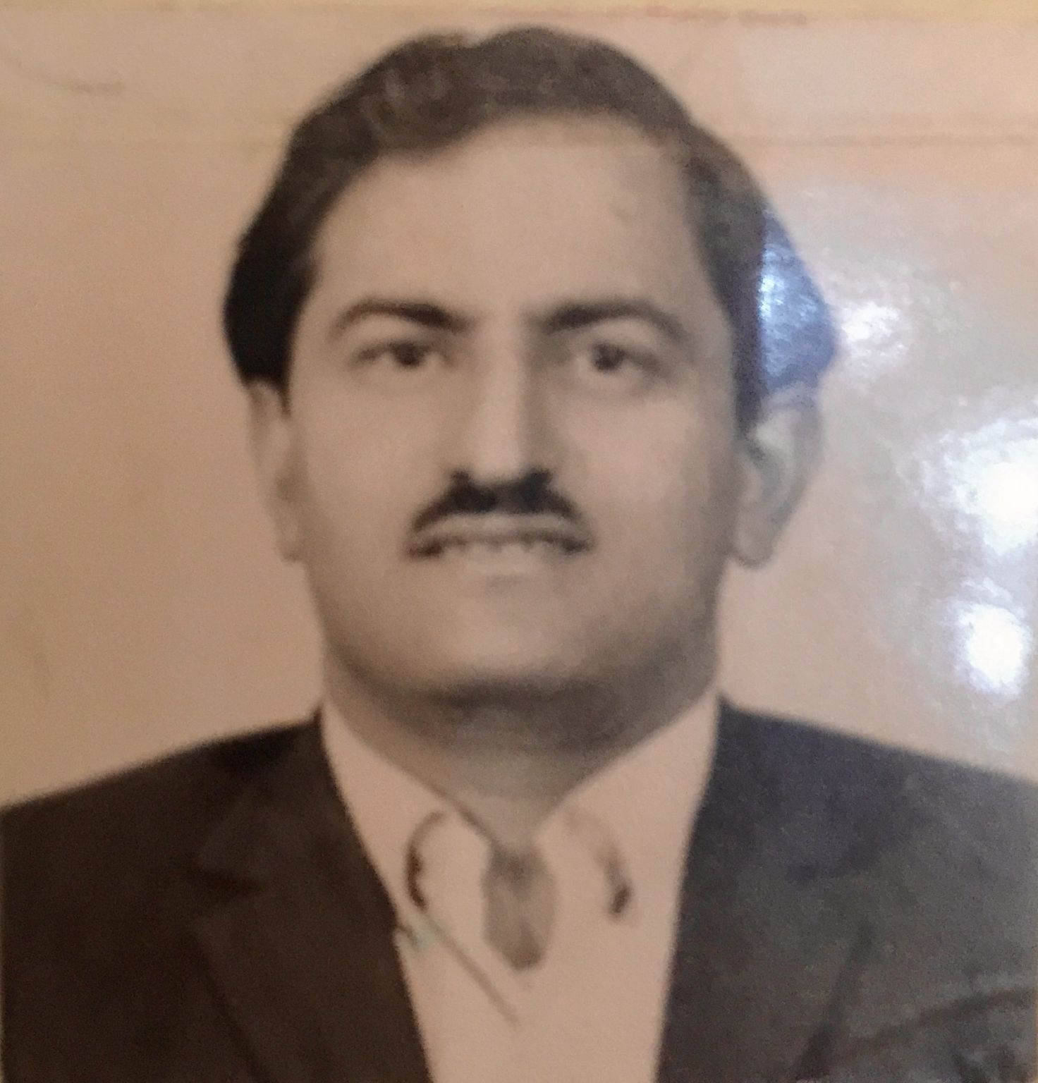 Black and white portrait of Ez Khan's father as a young man, wearing a suit and tie